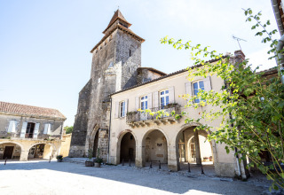 Plaza histórica cerca de Cazaubon, Occitania, Francia, con edificios de piedra antiguos y torre de iglesia.