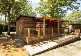Houten vakantiewoning met ruim terras in het groen, gefotografeerd bij Huttopia Lac de l'Uby - Gers, Occitanië, Frankrijk.