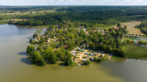 Vista aerea di Huttopia Lac de l'Uby - Gers, villaggio vacanze sul lago circondato da boschi in Occitania, Francia.