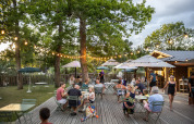 Udendørs terrasse på Huttopia Lac de l'Uby - Gers, med folk der nyder aftenen under lyskæder i Frankrig.