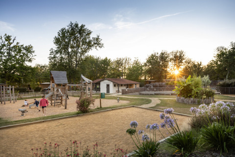 Zona de juegos y jardines al atardecer en el parque vacacional Huttopia Lac de l'Uby - Gers, Occitania, Francia.