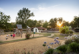 Speelplein en tuin bij zonsondergang in vakantiepark Huttopia Lac de l'Uby - Gers, Occitanië, Frankrijk.
