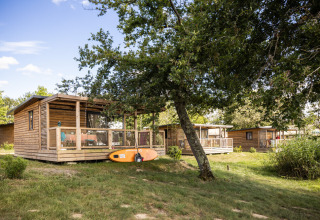 Houten chalets op vakantiepark Huttopia Lac de l'Uby in Occitanië, Frankrijk, omgeven door groen.