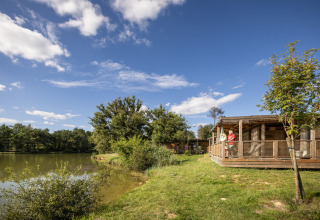 Houten chalet aan het meer bij Huttopia Lac de l'Uby - Gers vakantiepark, omgeven door natuur in Occitanië, Frankrijk.