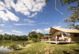 Glamping tent by the lake at Huttopia Lac de l'Uby, Gers, Occitanie, France, on a sunny day.
