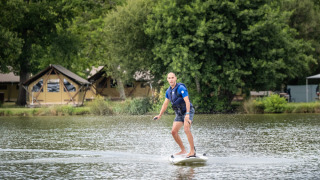Mann fährt auf einem E-Surfbrett auf dem See bei Huttopia Lac de l'Uby - Gers in Occitanie, Frankreich.