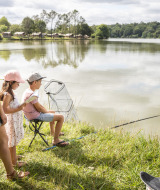 Familia pescando junto al lago en Huttopia Lac de l'Uby - Gers, un parque vacacional en Occitania, Francia.
