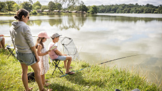 Familie angelt am Seeufer im Huttopia Lac de l'Uby - Gers, einem Ferienpark in Okzitanien, Frankreich.