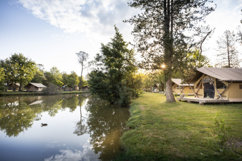 Tiendas glamping junto al lago en Huttopia Lac de l'Uby - Gers, rodeadas de árboles en Occitania, Francia.