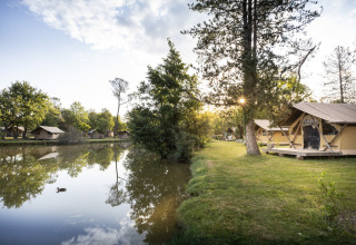 Tentes glamping au bord du lac à Huttopia Lac de l'Uby - Gers, entourées d’arbres en Occitanie, France.