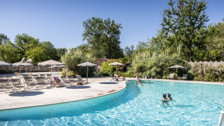Schwimmbad im Freien im Huttopia Lac de l'Uby - Gers Ferienpark, umgeben von Liegestühlen und Bäumen.
