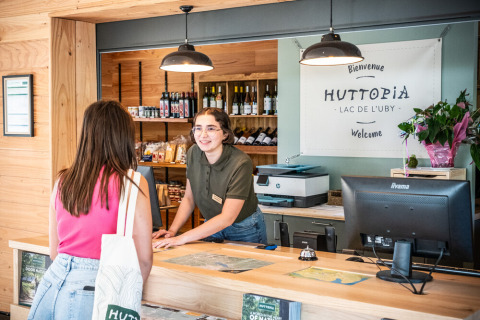 Receptionist greeting a guest at Huttopia Lac de l'Uby holiday park in Occitanie, France, check-in.