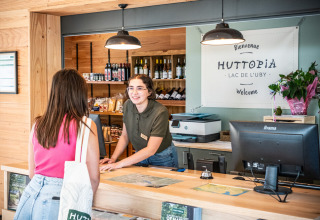 Receptionist byder gæst velkommen på Huttopia Lac de l'Uby i Gers, Occitanien, Frankrig, feriepark.