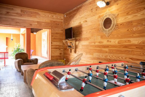 Sala interior en Camping Valkenburg - Maastricht con futbolín, sillones y paredes decoradas de madera.
