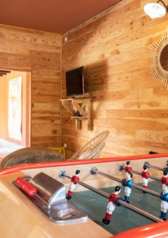 Sala interior en Camping Valkenburg - Maastricht con futbolín, sillones y paredes decoradas de madera.