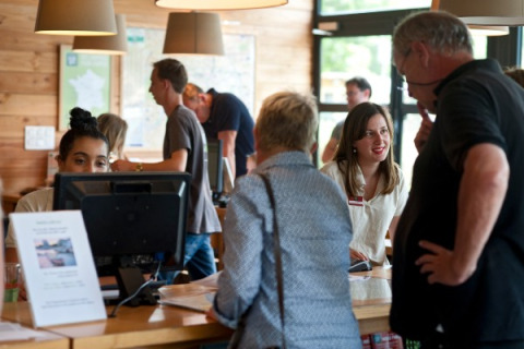 Personal de recepción atiende a huéspedes en Camping Valkenburg - Maastricht, parque vacacional en Limburg.