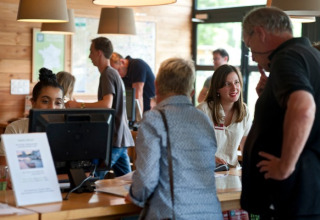 Personal de recepción atiende a huéspedes en Camping Valkenburg - Maastricht, parque vacacional en Limburg.