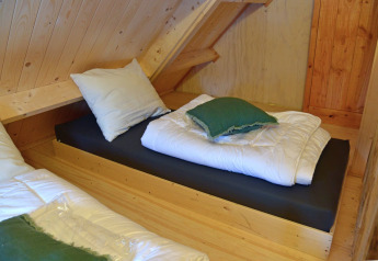 Cozy wooden room with single beds inside Ooievaarsnest tree house at Camping de Koeksebelt, Netherlands.