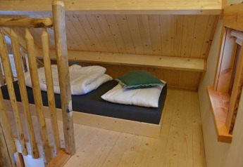 Cozy sleeping nook in Ooievaarsnest treehouse at Camping de Koeksebelt, Netherlands, featuring wood decor.