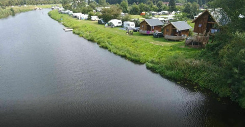 Aerial view of Ooievaarsnest tree house and caravans by the river at Camping de Koeksebelt in the Netherlands.