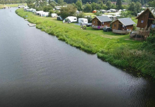 Aerial view of Ooievaarsnest tree house and caravans by the river at Camping de Koeksebelt in the Netherlands.