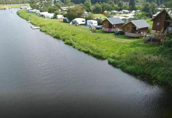 Luchtbeeld van Ooievaarsnest boomhut en caravans langs de rivier op Camping de Koeksebelt, Nederland.