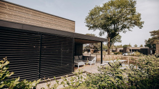 Vista exterior de una lujosa cabaña en Soof Retreats, Países Bajos, con terraza y muebles de jardín modernos.