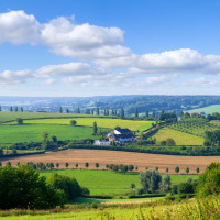 Vista panorámica de campo verde y ondulado con alojamientos glamping y campos bajo un cielo azul despejado.