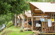Tiendas tipo safari con terrazas de madera y ropa tendida en el camping Petite Suisse de Bélgica.