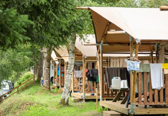 Tiendas tipo safari con terrazas de madera y ropa tendida en el camping Petite Suisse de Bélgica.