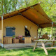 Safari tent Comet with wooden deck, bicycle, outdoor seating, and picnic table in a lush green setting.