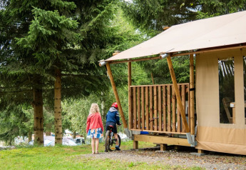 Two children play outside a safari tent named Comet at Petite Suisse campground in Belgium.