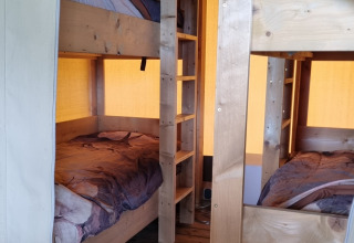 Interieur van een safaritent met houten stapelbedden op Boerderijcamping de Hinde in Nederland.