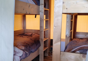 Interno di tenda safari con letti a castello in legno a Boerderijcamping de Hinde nei Paesi Bassi.
