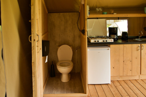Safari tent interior with private toilet, kitchenette, and mini fridge at Camping Catsop in the Netherlands.