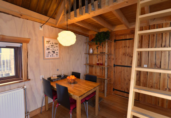 Vista interna della casa sull’albero al Camping de Koeksebelt nei Paesi Bassi con tavolo da pranzo e scala.