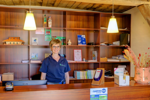 Receptionist står bag disken på Camping Dal van de Mosbeek, feriepark i Overijssel, Holland.