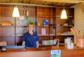 Receptionist står bag disken på Camping Dal van de Mosbeek, feriepark i Overijssel, Holland.