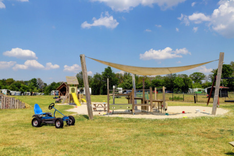 Spielplatz mit Rutsche, Kettcar und Sonnensegel im Camping Dal van de Mosbeek, Overijssel, Niederlande.