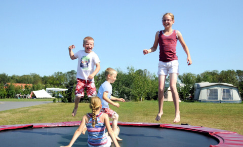 Kinder springen und spielen auf einem Trampolin im Camping Dal van de Mosbeek in Overijssel, Niederlande.