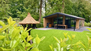 Family Lodge Deluxe en De Thijmse Berg, Países Bajos, con cabaña moderna y jardín verde frondoso.