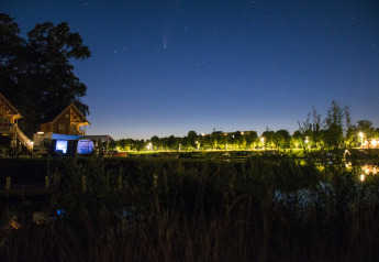 Night photo of the tree house at Camping de Koeksebelt in the Netherlands, with stars and reflections.