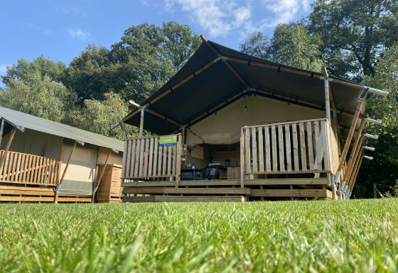 Safaritent met eigen sanitair op Camping Dal van de Mosbeek in Nederland, gezien vanaf het gras.