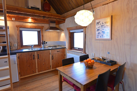 Accogliente cucina e zona pranzo in una casa sull'albero al Camping de Koeksebelt, Paesi Bassi, con arredi in legno.