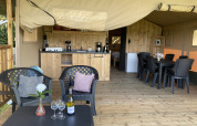 Innenansicht eines luxuriösen Safarizelts mit Küche, Essbereich und Sitzecke auf Camping Dal van de Mosbeek.