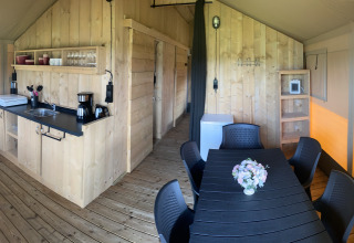 Interno di una tenda safari con cucina in legno e tavolo da pranzo al Camping Dal van de Mosbeek, Paesi Bassi.