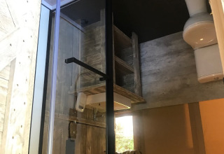Vista interna di un bagno in tenda safari al Camping Dal van de Mosbeek, con doccia e toilette visibili.