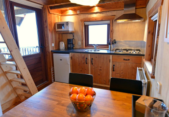 Moderne Küche und Essbereich im Baumhaus bei Camping de Koeksebelt, Niederlande, mit Obstschale.