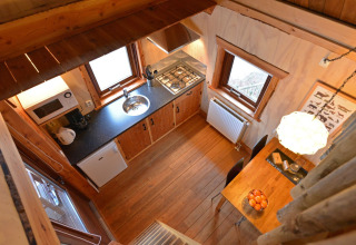 Gezellige boomhutkeuken met houten vloer, tafel en ramen gezien van boven bij Camping de Koeksebelt.