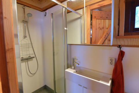 Baño moderno con ducha y lavabo en una casa del árbol en Camping de Koeksebelt, Países Bajos.